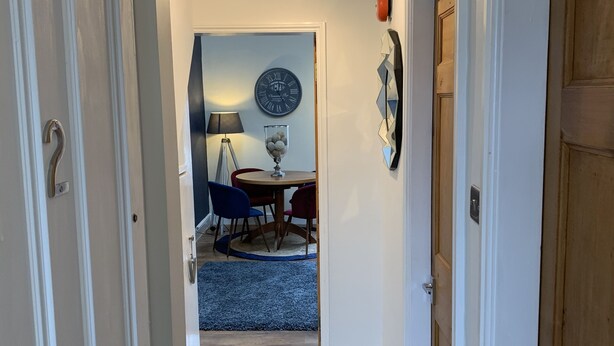 A hallway leading to a dining area with a clock and a lamp on the wall. - Remarkable 1-bed Apartment in Kirkby Lonsdale (Carnforth)
