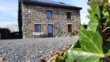 A stone building with a gravel driveway and a bench.