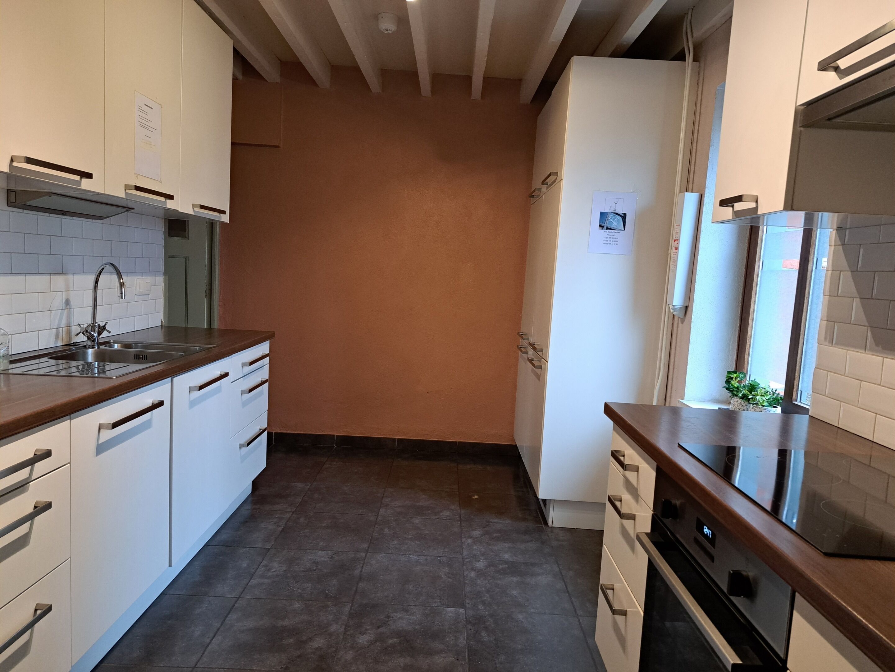 A kitchen with white cabinets, a stainless steel sink, and a built-in oven.