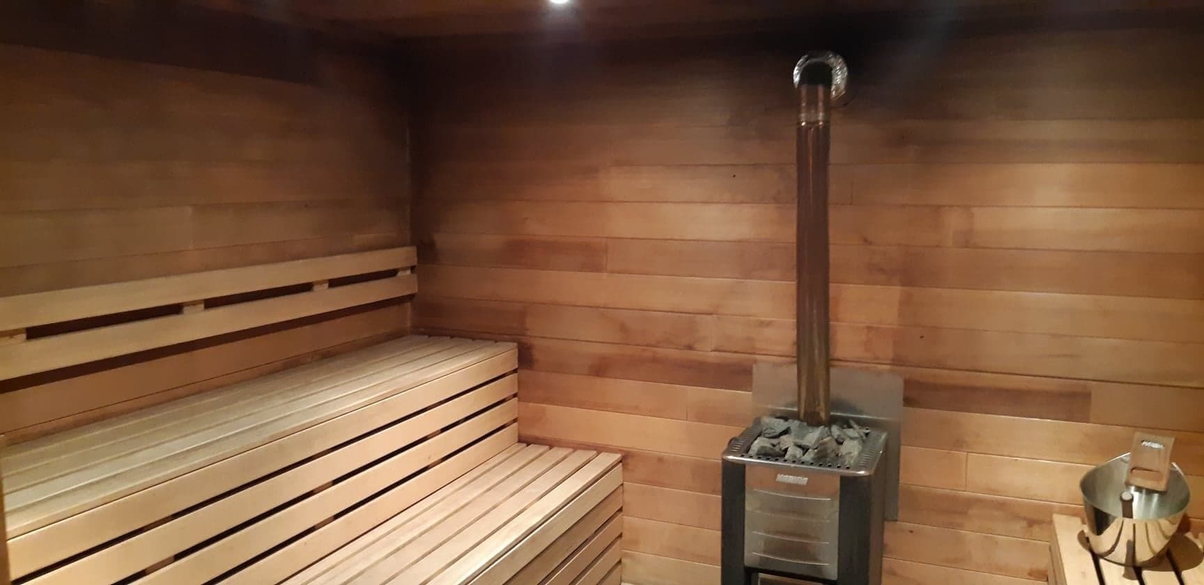 A sauna with wooden benches and a central heating unit.