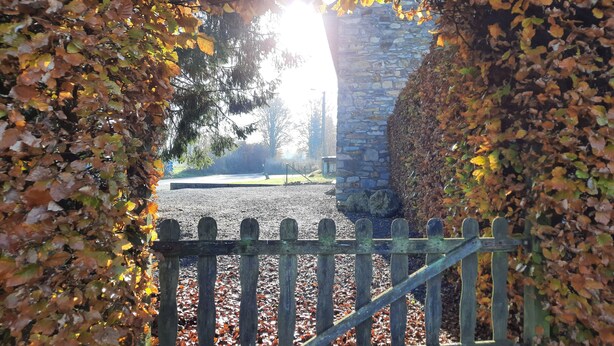 A stone wall with a wooden gate leading to a gravel path.
