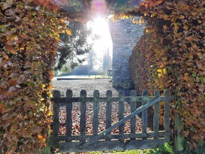 Un mur de pierres avec une porte en bois donnant sur un chemin de gravier.