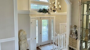 A grand entrance with a white staircase, a chandelier, and a glass display cabinet. - Our Most Popular Lakefront Home (Carbondale)