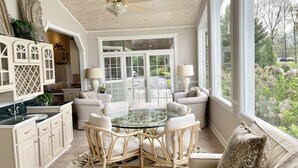 A spacious kitchen with white cabinetry, a dining area with a glass table, and a view of the outdoors. - Our Most Popular Lakefront Home (Carbondale)