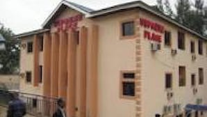 A multi-story building with a beige facade, several windows, and a visible entrance. - Room-supreme Place Hotel - Guest Room (Abuja)