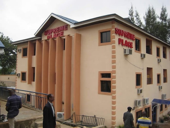 A building with 'SUPREME PLACE' signage, multiple windows, and air conditioning units.