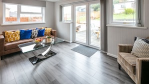 Un salon moderne avec un canapé en cuir marron, une table basse en verre et un fauteuil à rayures.