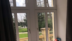 Une pièce avec une grande fenêtre, un radiateur et un lit avec un oreiller.