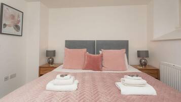 Un dormitorio con una cama grande, dos mesitas de noche y un cuadro enmarcado en la pared.