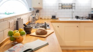 A kitchen with a wooden countertop, a bowl of fruit, a loaf of bread, and a book. - Kensington Chapel Apartments in Bath  (Bath)
