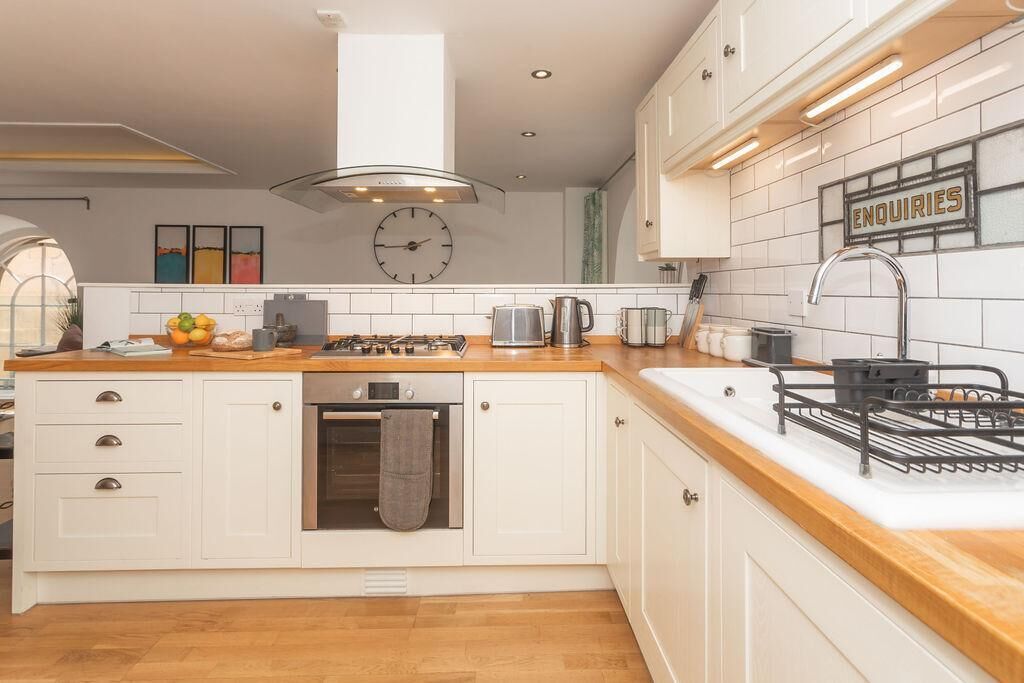 A modern kitchen with white cabinetry, a wooden countertop, a gas stove, and a sink.