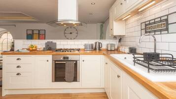 A modern kitchen with white cabinetry, a wooden countertop, a gas stove, and a sink.