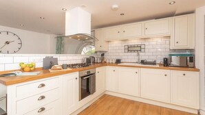 A modern kitchen with white cabinets, a wooden countertop, a built-in oven, and a microwave. - Kensington Chapel Apartments in Bath  (Bath)