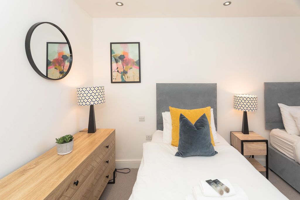 Ein modernes Schlafzimmer mit Bett, Nachttischen, einer Kommode und Wandbildern.