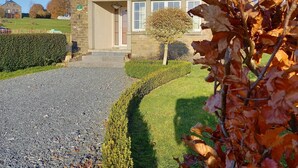 Una casa de piedra de dos pisos con entrada pavimentada y césped cuidado.