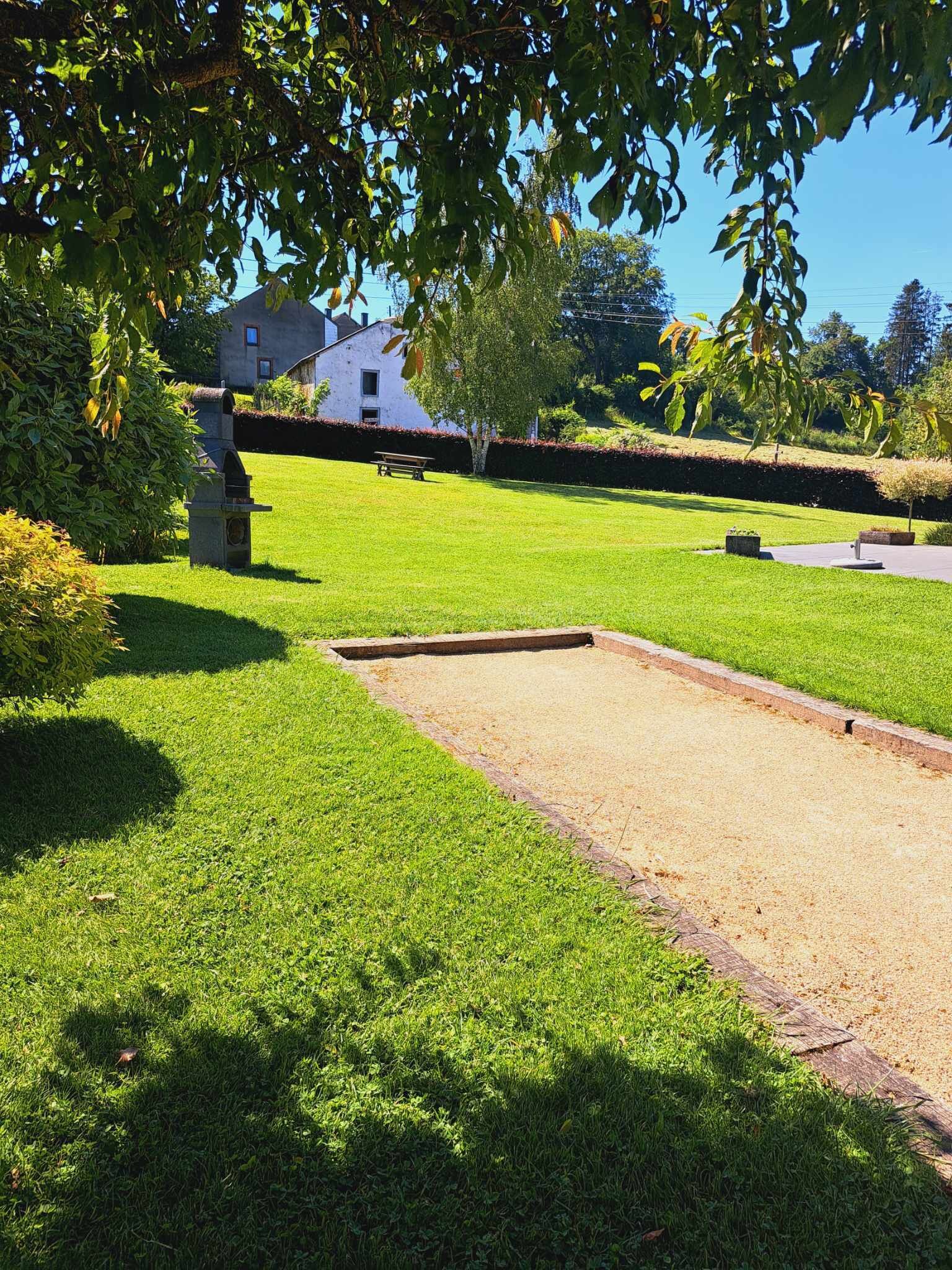 A well-maintained lawn with a croquet court, a stone bench, and a house in the background.