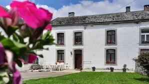 A white building with multiple windows and a door, surrounded by a well-maintained lawn and potted plants. - Le Relais du Cheval Blanc (Tenneville)