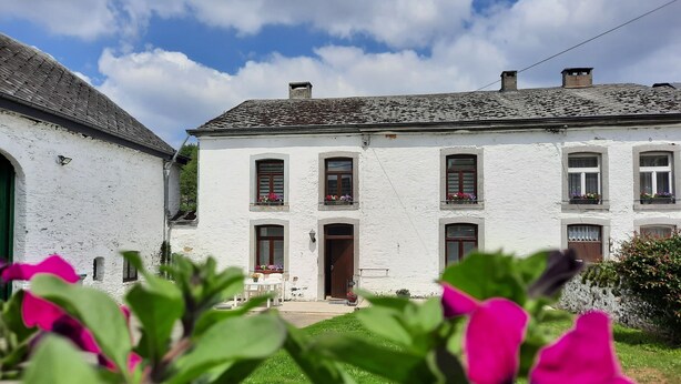 A white building with multiple windows and a door, surrounded by greenery. - Le Relais du Cheval Blanc (Tenneville)