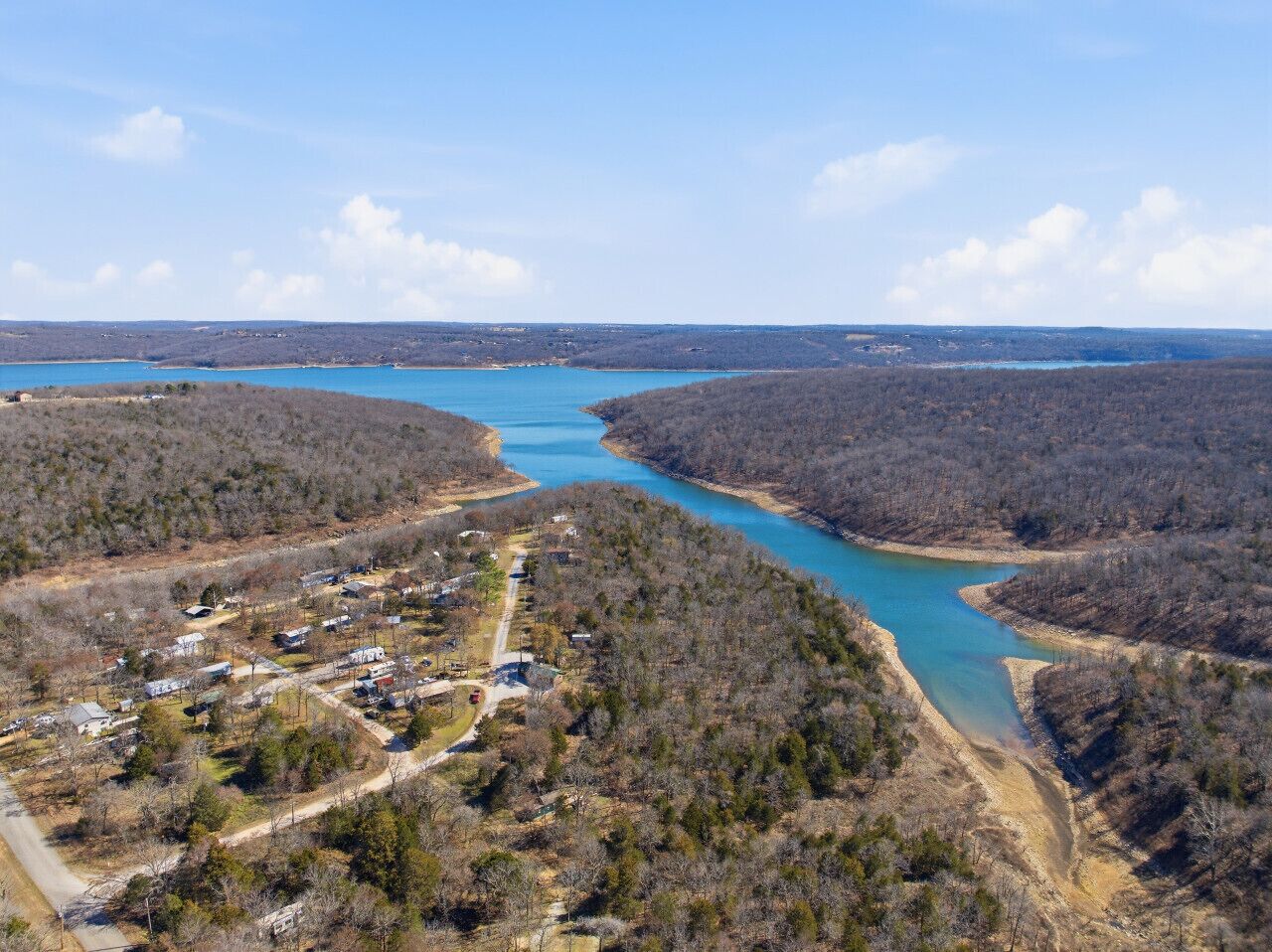 Vue aérienne d’une communauté riveraine, avec des maisons le long du rivage et un lac d’un bleu limpide.