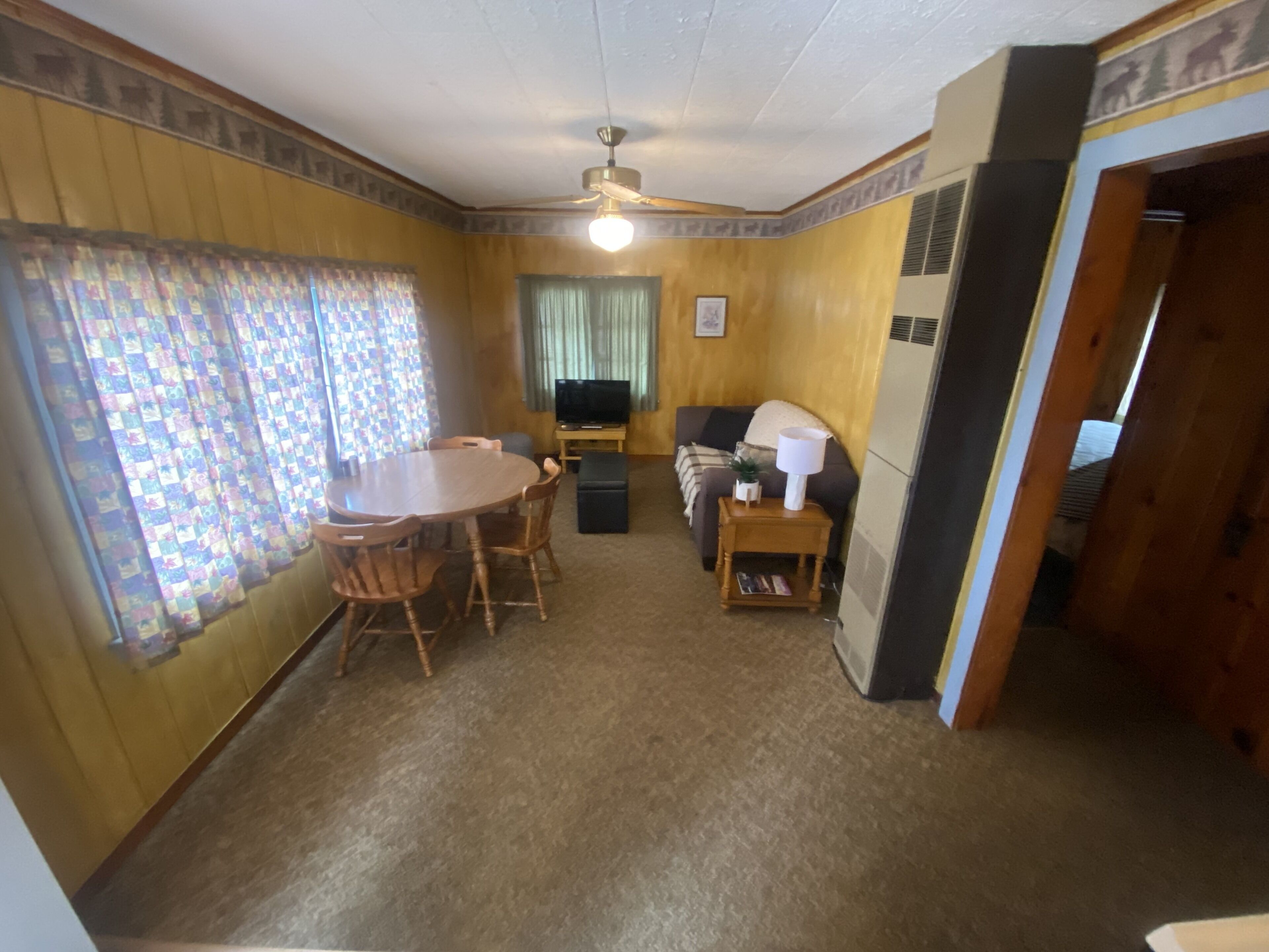 A living room with a dining table, chairs, a sofa, and a television.