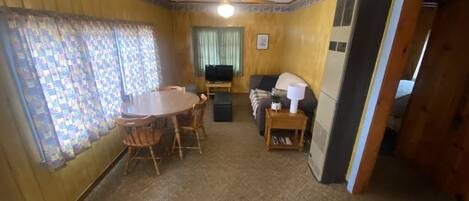 A living room with a dining table, chairs, a sofa, and a television.