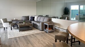 Uma sala de estar moderna com um sofá seccional, uma mesa de centro e uma área de jantar com mesa redonda e cadeiras.