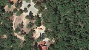 An aerial view of a property with a red-roofed building, a dirt path, and dense surrounding forest. - Cozy house 1.1 miles away from Dark Day boat launch at Bullards Bar Reservoir  (Camptonville)