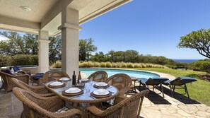 An outdoor dining area with wicker furniture and a pool in the background.