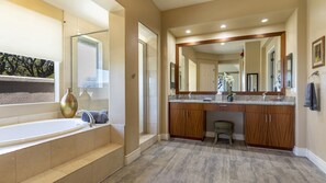 A bathroom with a bathtub, vanity, and a large mirror.