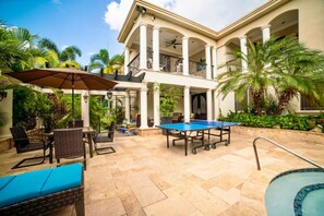 A pool area with a ping pong table, lounge chairs, and a covered seating area with umbrellas. - Orchids & Palms Villa, Chef, Pool-Montego Bay! (Montego Bay)