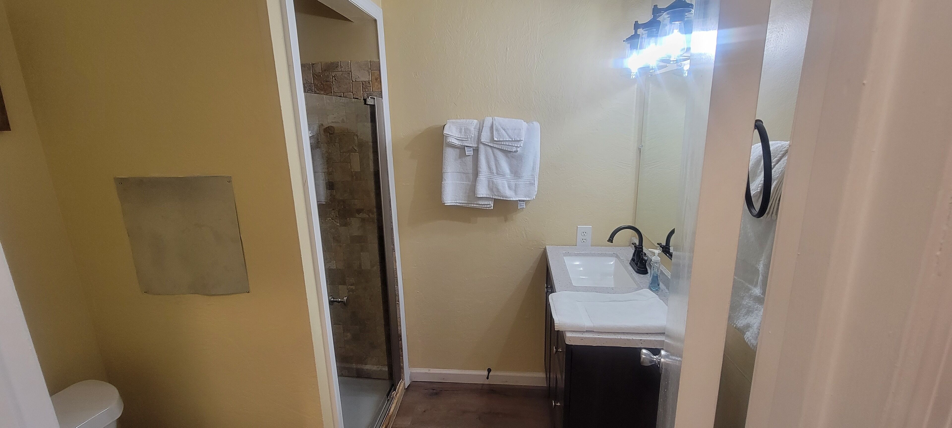 A bathroom with a shower, a sink, and a mirror.