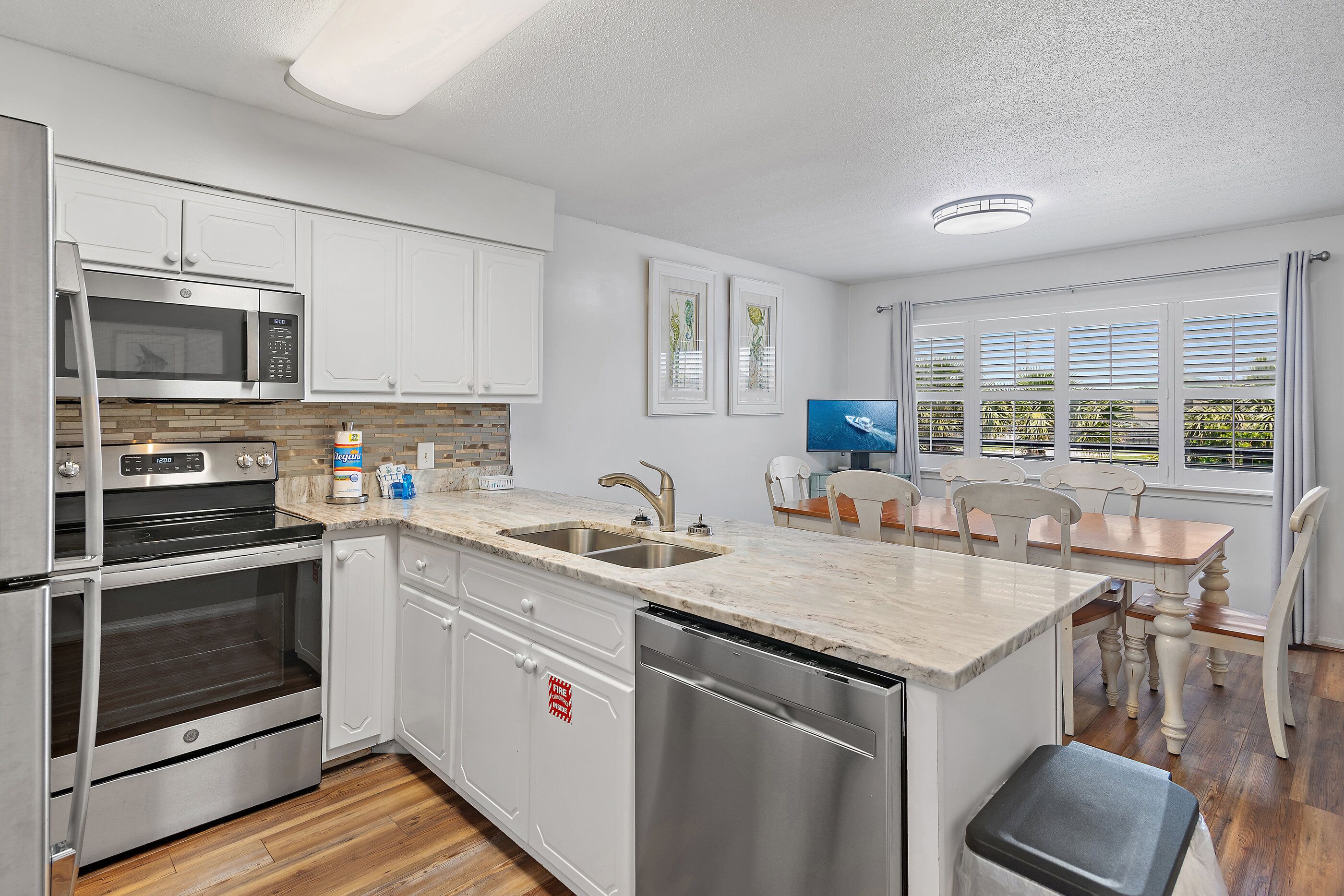 A modern kitchen with stainless steel appliances, a dishwasher, and a dining area with a table and chairs.