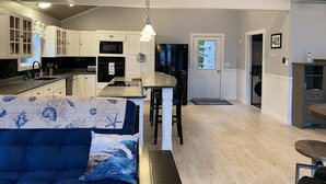 Una cocina moderna con armarios blancos, una isla central y una zona de comedor con un sofá azul.