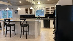 Una cocina moderna con armarios blancos, un refrigerador negro y techo de madera.