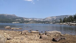 Eine felsige Küstenlinie mit einem See und Bergen im Hintergrund.