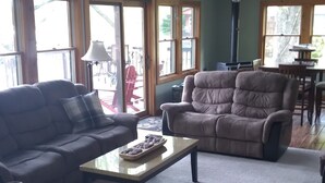 Una sala de estar con sofá, sillón, mesa de centro y un comedor con mesa y sillas.