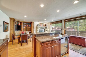 A spacious kitchen with wooden cabinets, a granite countertop, and a fireplace. - Updated Condo: Walk to Vail Village & Ski Shuttle! (Vail)