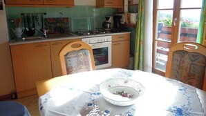 A kitchen with wooden cabinets, a stove, and a window with curtains.