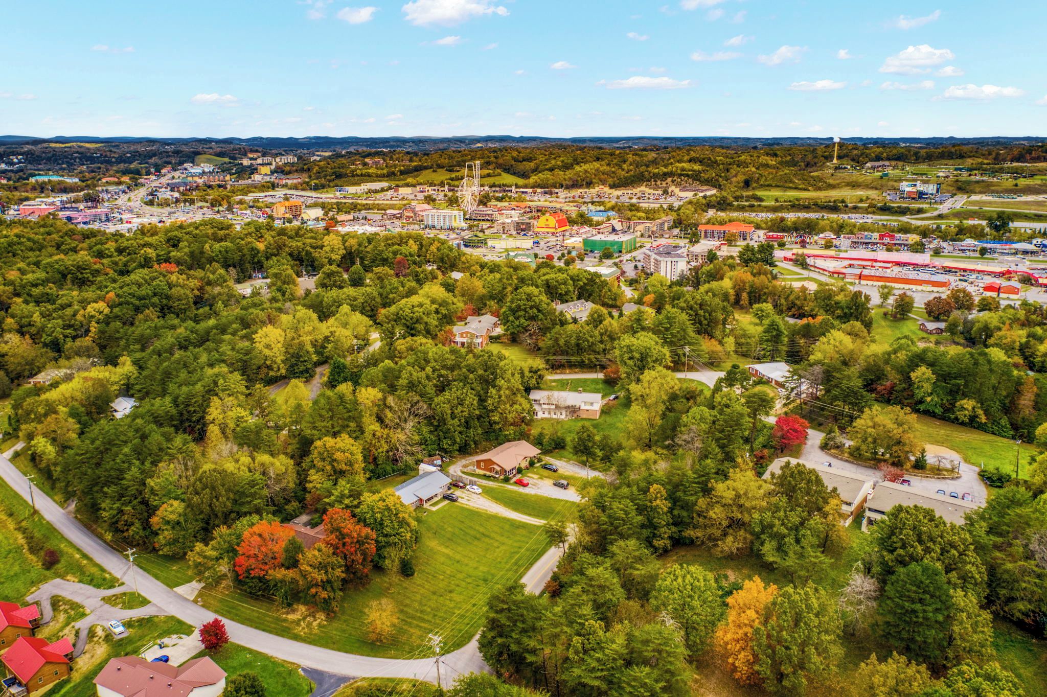 Vue aérienne d’un quartier résidentiel avec des maisons, des rues et un grand complexe commercial.