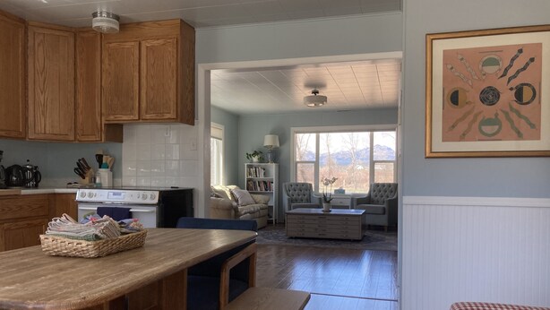 Una cocina con armarios de madera, una estufa y una zona de comedor con banco y mesa.
