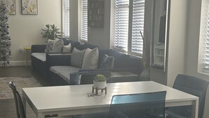 A modern living room with a white dining table, black chairs, a blue sofa, and a Christmas tree.