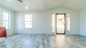 A spacious room with large windows, a door leading outside, and a ceiling fan. - Pleasanton Executive Inn By OYO (Pleasanton)