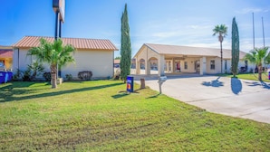 A building with a red roof, a grassy lawn, and a sign that says "ENTER". - Pleasanton Executive Inn By OYO (Pleasanton)
