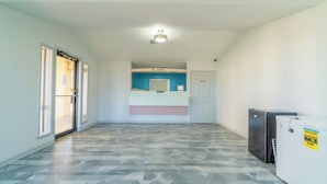 A hallway with a registration desk, a door, and a refrigerator. - Pleasanton Executive Inn By OYO (Pleasanton)