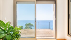 A room with a sliding glass door leading to a balcony with a view of the sea. - Villa Beachfront - Herce Property by Priority (Llucmajor)