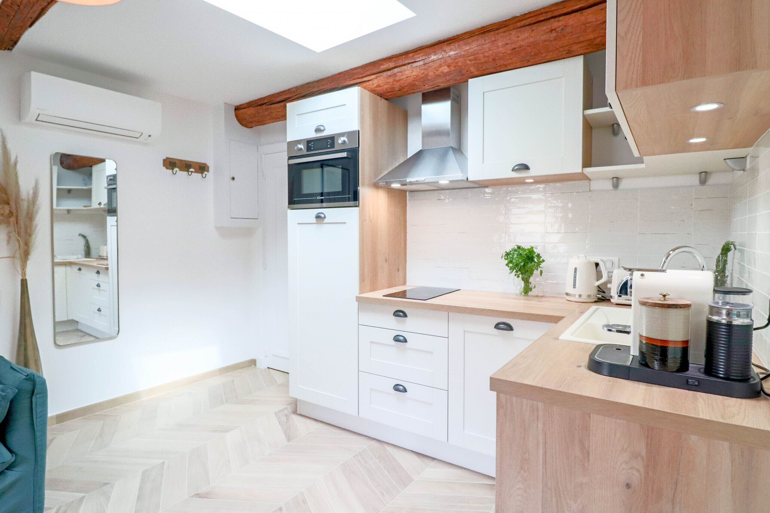 Une cuisine moderne avec des armoires blanches, un plan de travail en bois et un four encastré.