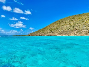 A coastal landscape with clear turquoise waters and a hilly terrain in the background. - Mojito Hill - private hilltop pool oasis! (East End)