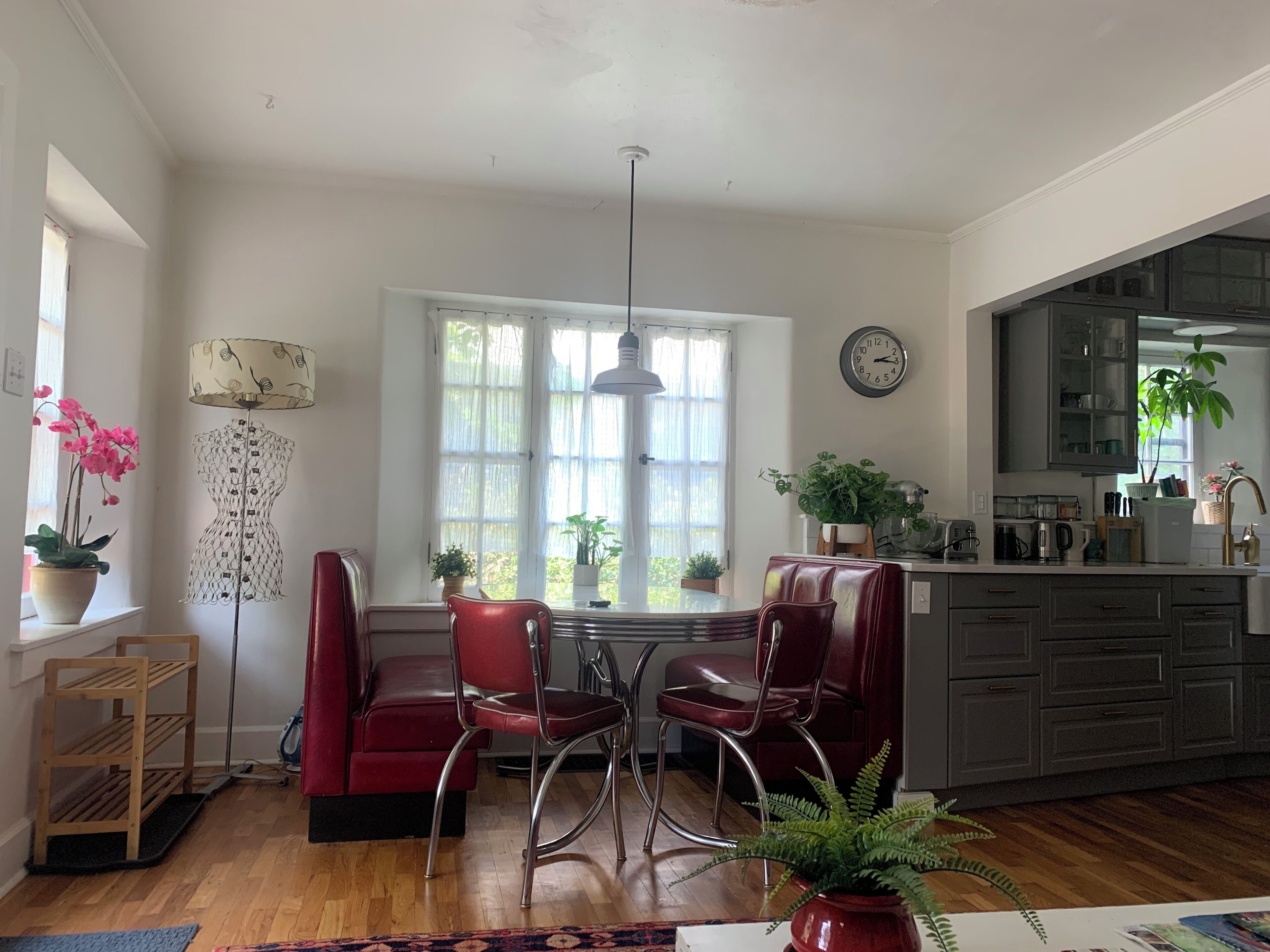 A modern kitchen with a dining area, wooden flooring, and a large window providing natural light.