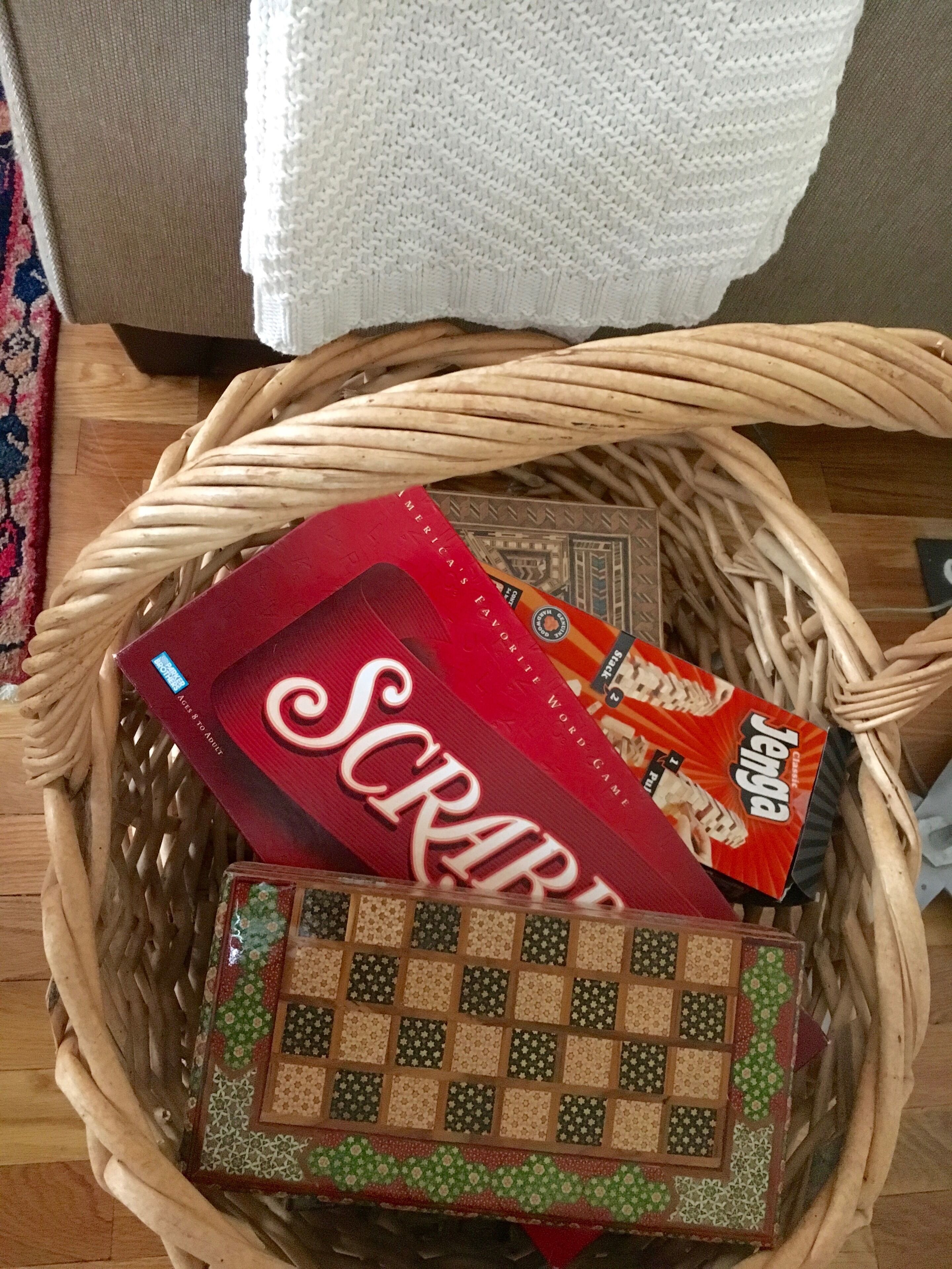 A wicker basket containing a Scrabble game and a box of Jenga.