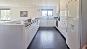 A modern kitchen with white cabinets, a black countertop, and a large refrigerator. - A Yingina Getaway, Home of Brown Trout (Miena)